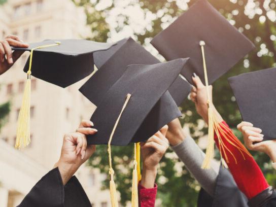 photo of group of graduates throwing graduation caps in the air